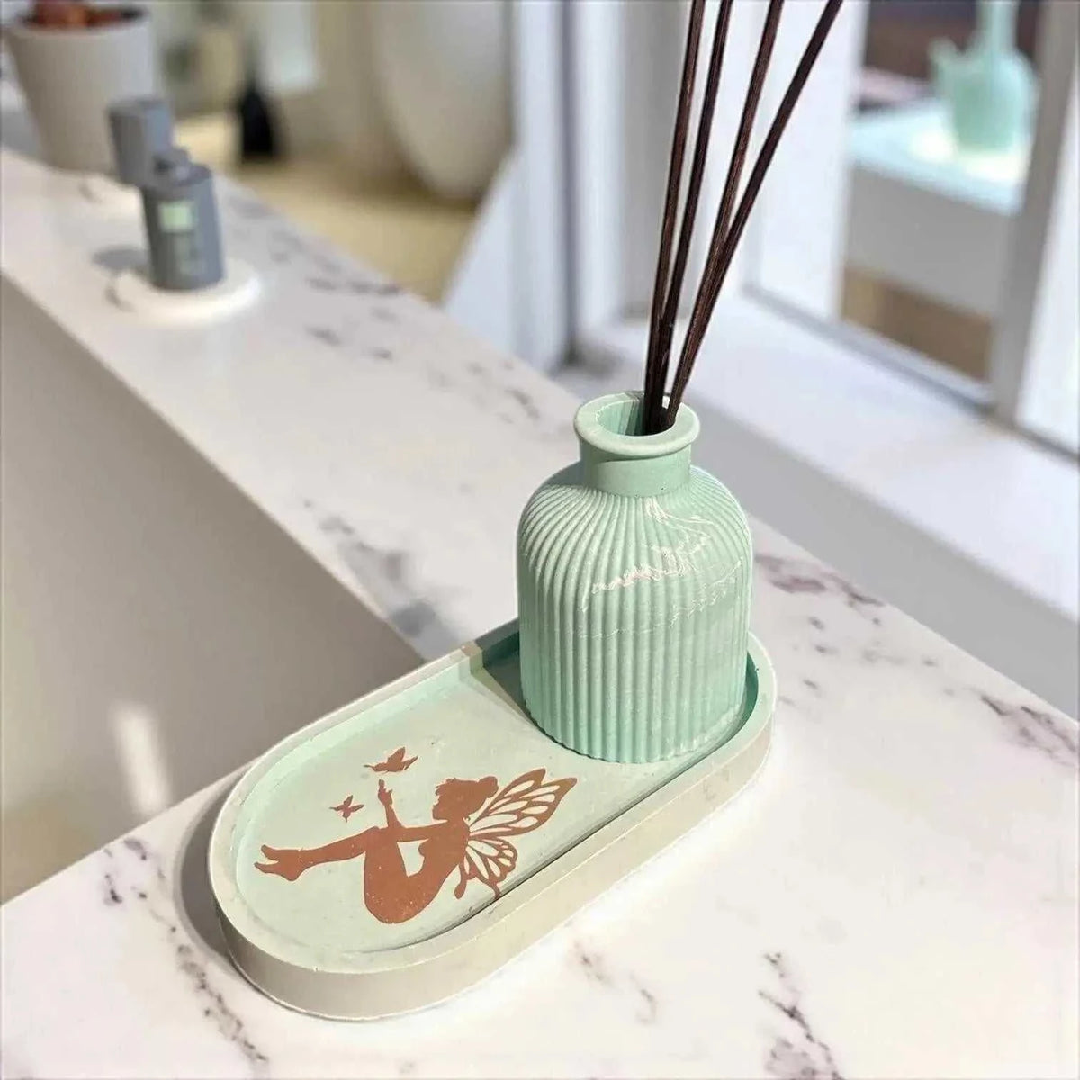 Diffuseur à parfum vert d’eau en Jesmonite, design côtelé, plateau avec silhouette fée cuivrée, finition mate et lisse.