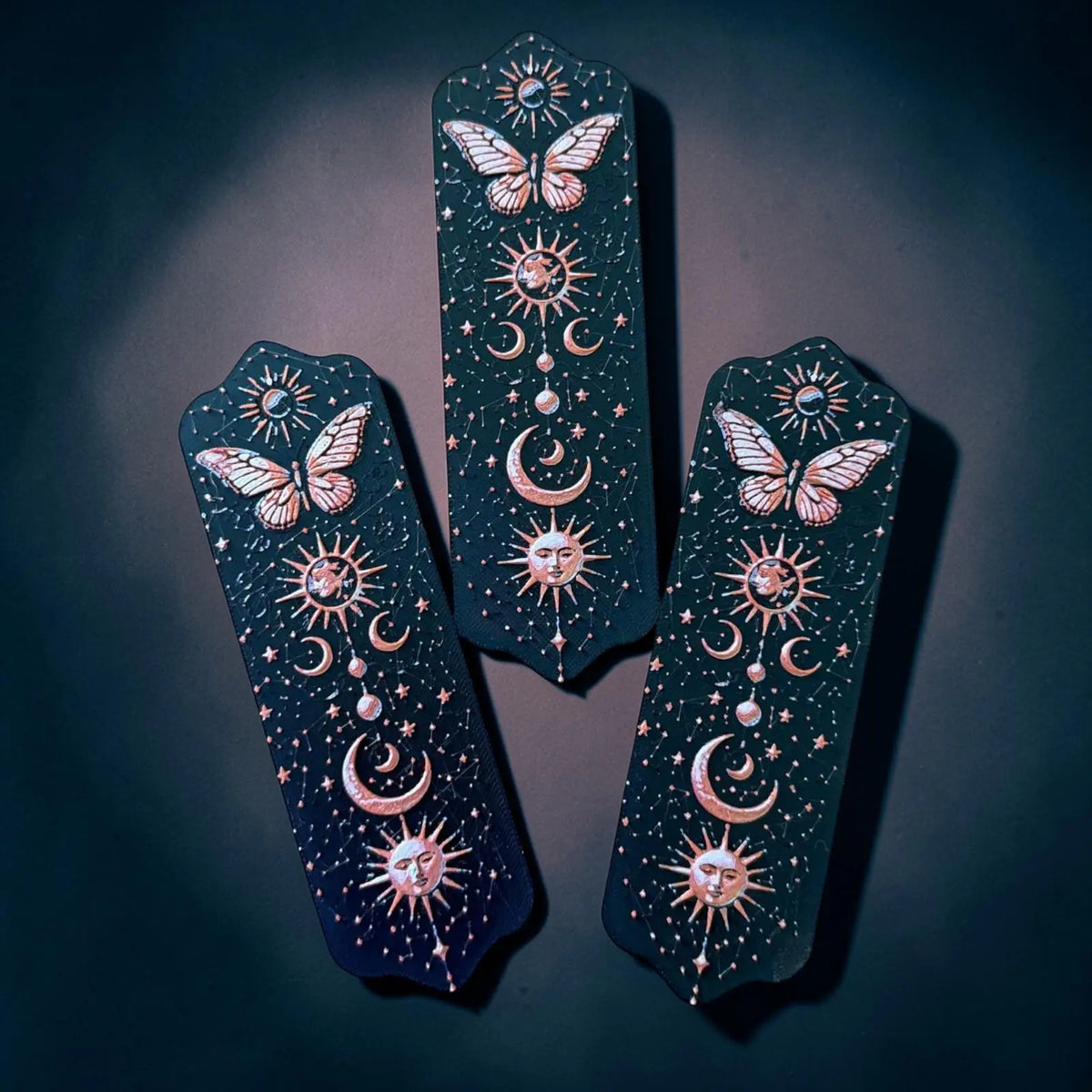 Marque-page papillon céleste en impression 3D avec motifs lune, soleil et étoiles sur fond noir
