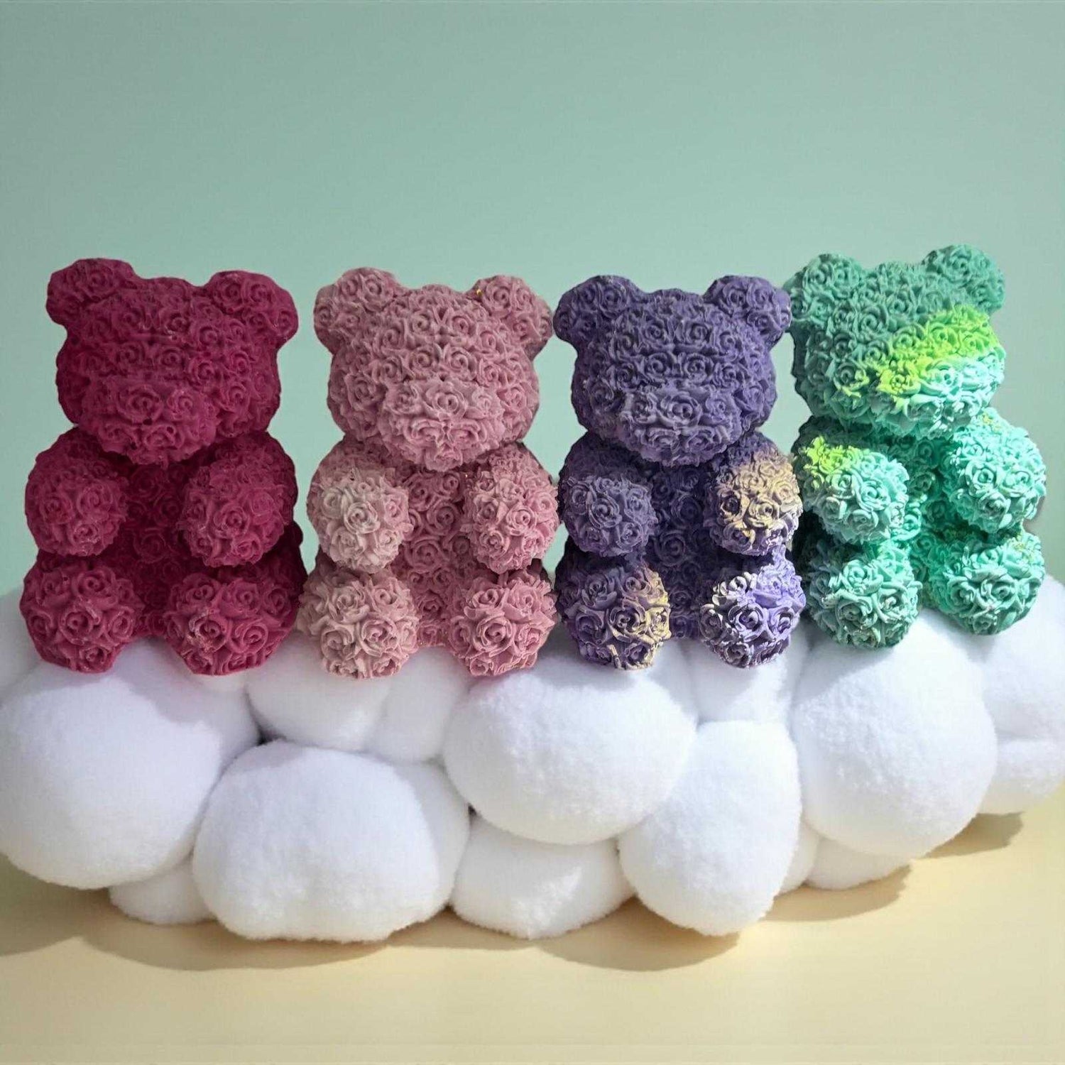 Quatre ours en peluche recouverts de roses en rose violet et vert sur une base blanche du coffret ambiance cadeaux