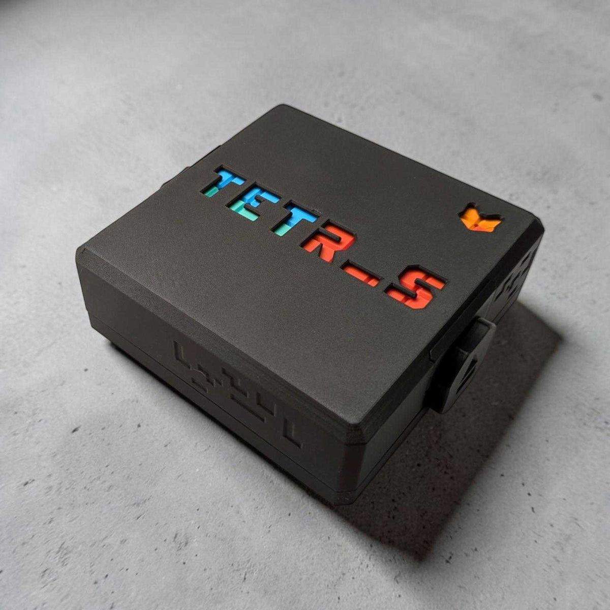Appareil noir rectangulaire avec logo tetris illuminé en bleu vert et orange dans la collection ambiance créations 3d