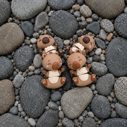Quatre capybaras articulés kawaii présentés sur des galets gris