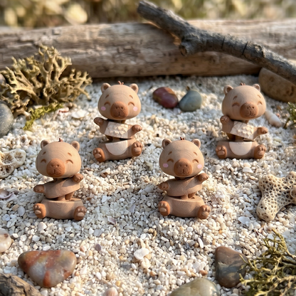 Quatre capybaras kawaii articulés présentés dans un décor naturel de coquillages