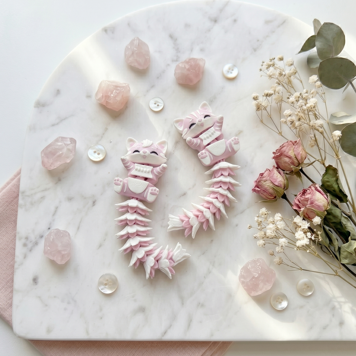 Deux chats articulés kawaii avec queues duveteuses dans un décor marbré fleuri