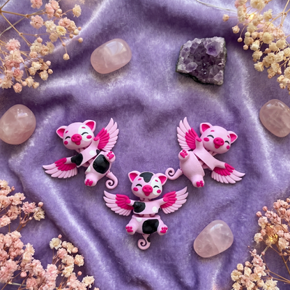 Trois cochons ailés flexi articulés kawaii sur fond velours violet avec pierres roses