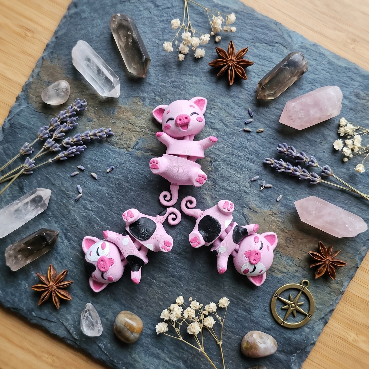 Trois cochons articulés kawaii roses disposés parmi des cristaux
