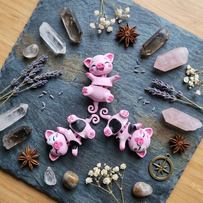 Trois cochons articulés kawaii roses disposés parmi des cristaux