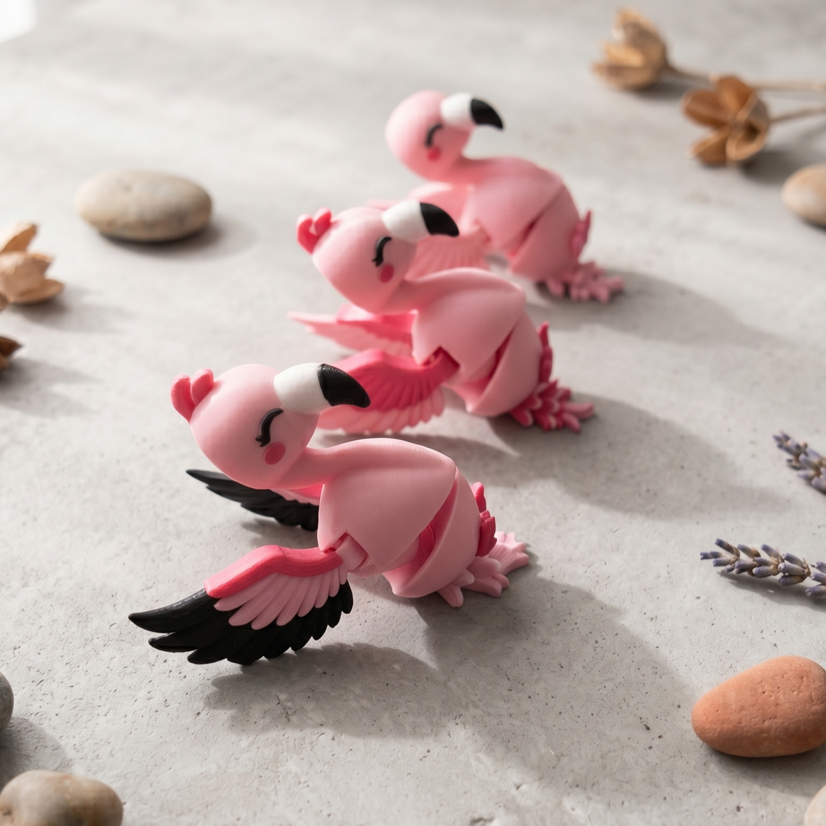 Trois porte-clés flamants roses articulés présentés sur un décor minéral