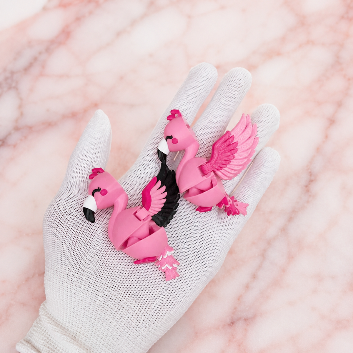 Deux modèles de flamants roses articulés kawaii avec ailes colorées dans une main