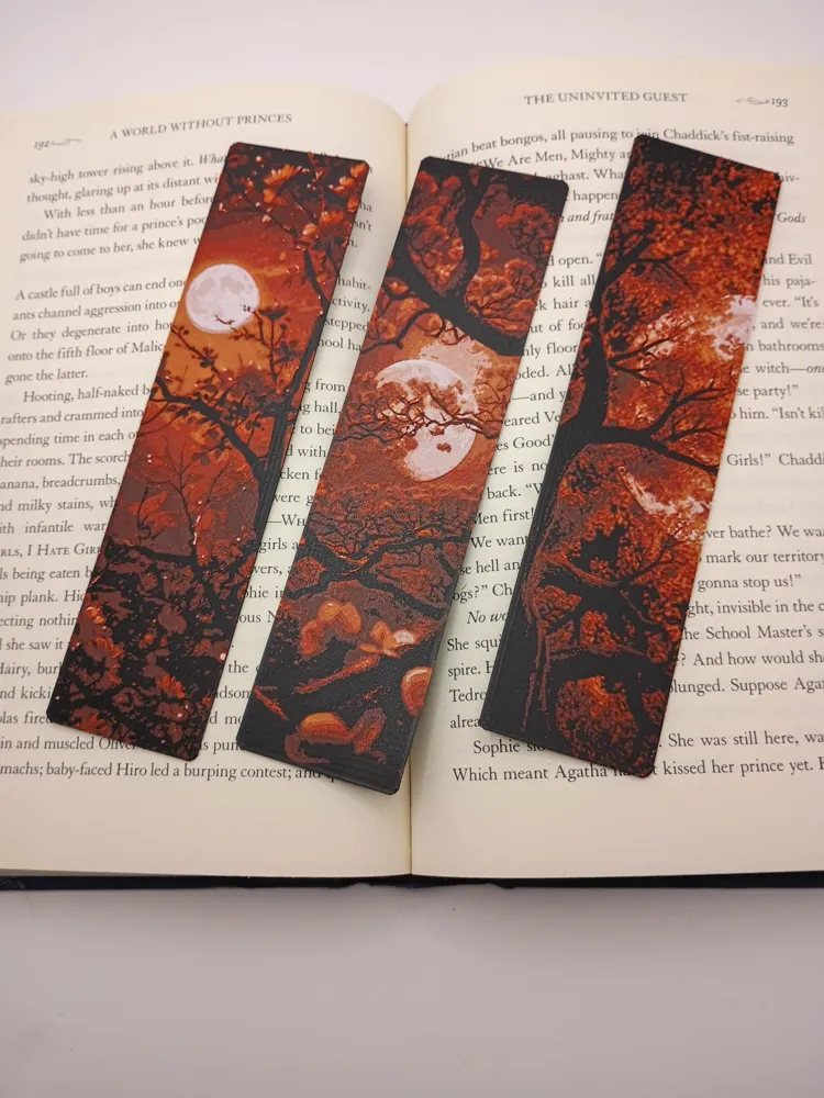 Trois marque-pages 3D Fleurs de la Lune de Sang posés sur un livre ouvert