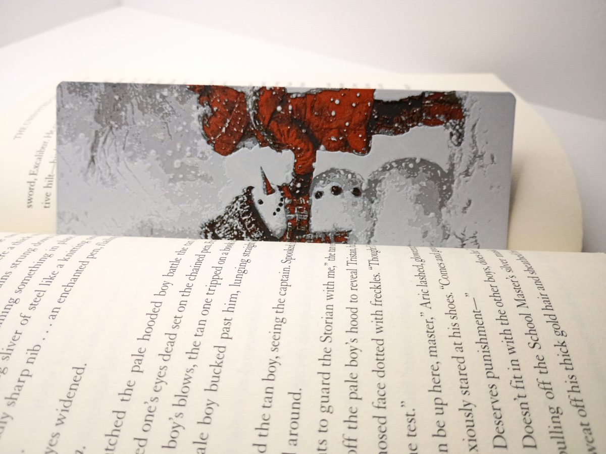 Marque-page de Noël modèle fille construisant un bonhomme de neige placé dans un livre