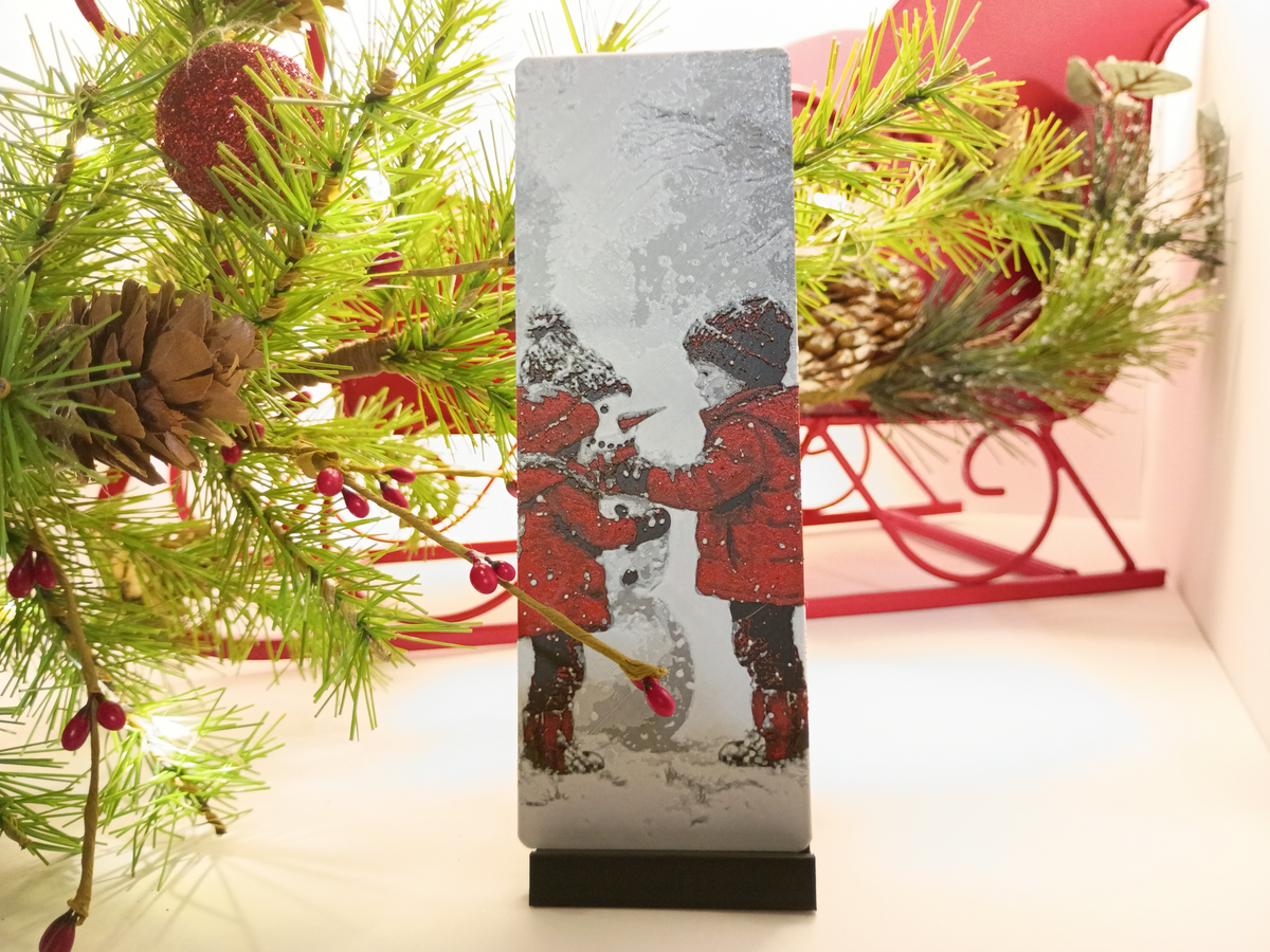 Marque-page de Noël frère et sœur avec bonhomme de neige présenté près d'un sapin décoré