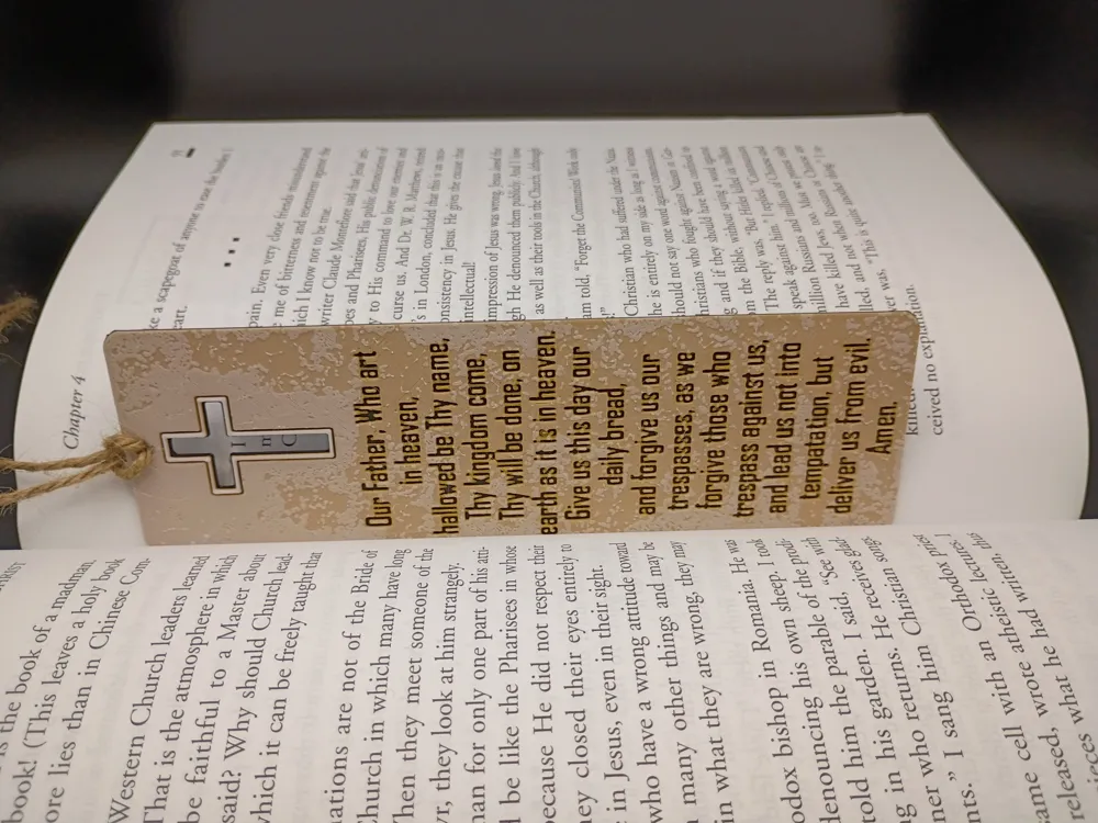 Marque-page Notre Père beige inséré dans un livre