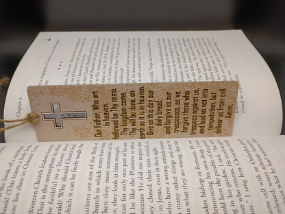 Marque-page Notre Père beige inséré dans un livre