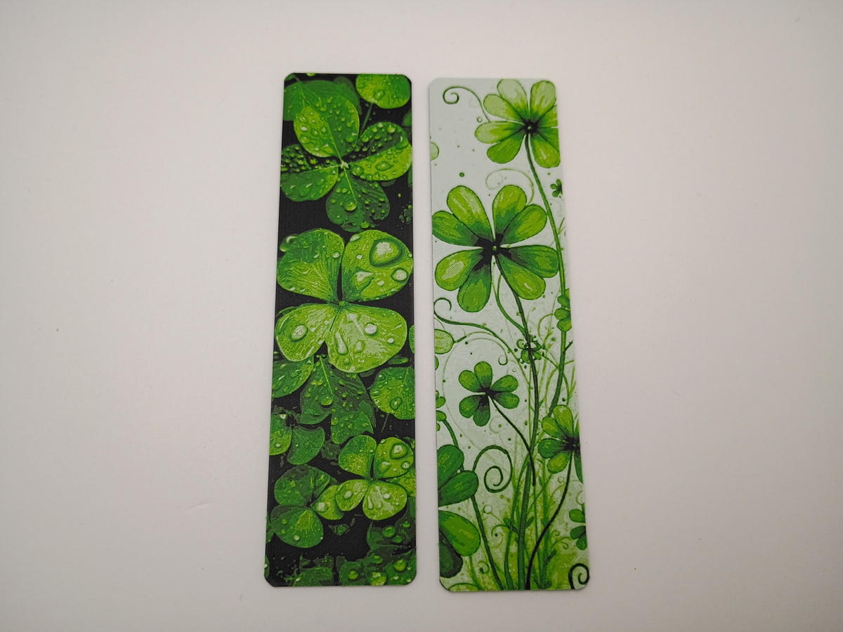 Les deux modèles Lucky Clovers côte à côte : trèfles réalistes sur fond noir et trèfles artistiques sur fond clair