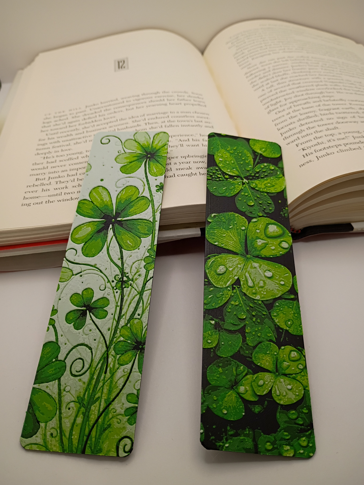 Marque-pages Lucky Clovers posés sur un livre ouvert, modèles trèfles fond clair et fond noir