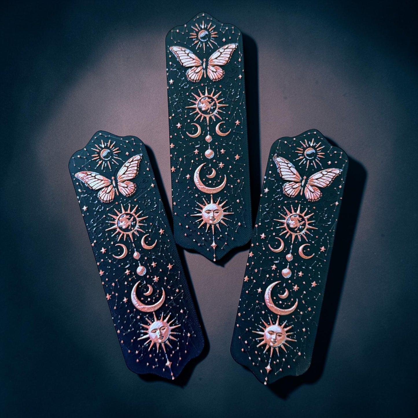 Marque-page papillon céleste en impression 3D avec motifs lune, soleil et étoiles sur fond noir