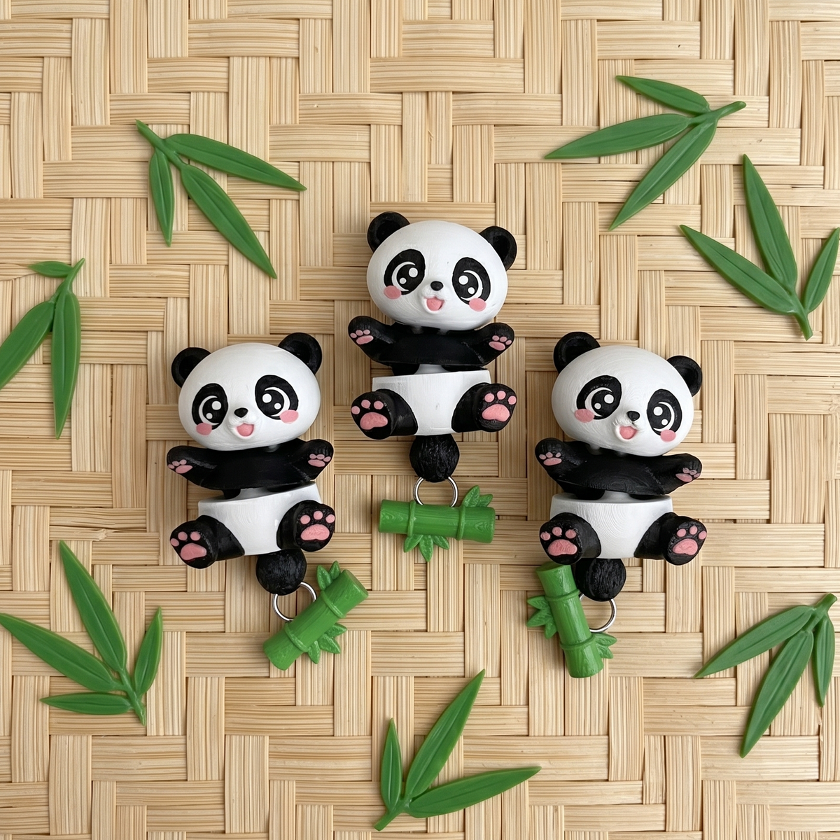 Trois pandas articulés noirs et blancs avec bambous verts sur un fond tressé