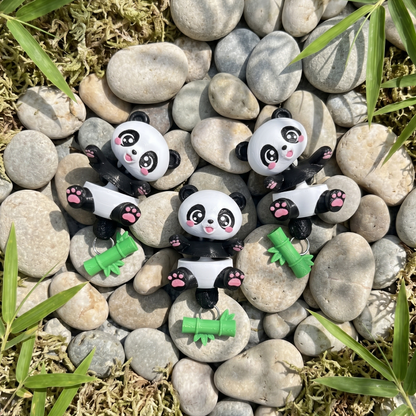 Trois porte-clés pandas articulés avec bambou détachable présentés sur des galets