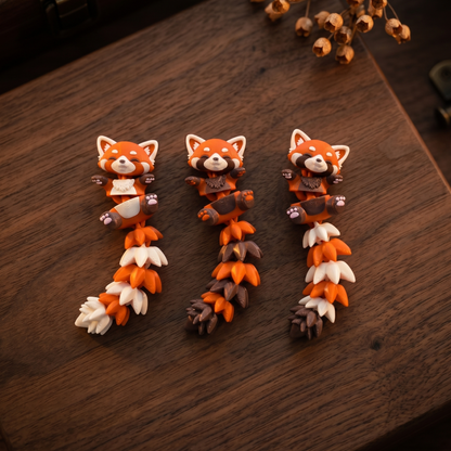 Trois pandas roux articulés avec queue claire, foncée ou tricolore sur fond en bois
