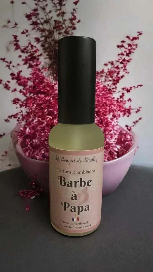 Parfum d’ambiance Barbe à papa en verre translucide avec étiquette rose pâle, bouchon noir mat, motifs sucrés et fleuris roses.