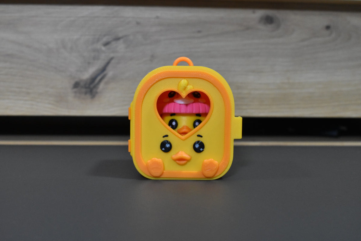 Pocket Pals Canard visible dans la fenêtre cœur de sa mini maison jaune