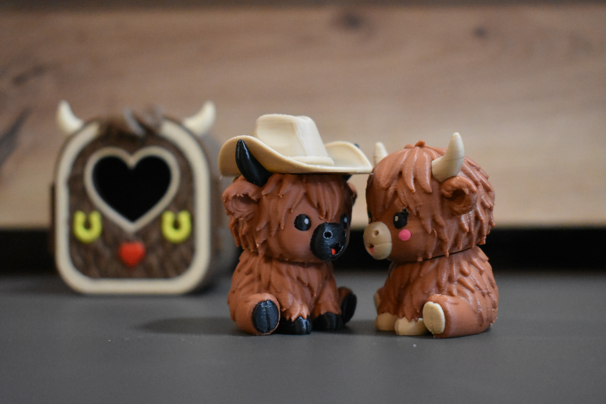 Pocket Pals Highland Cow deux figurines 3D kawaii avec et sans chapeau devant leur mini maison