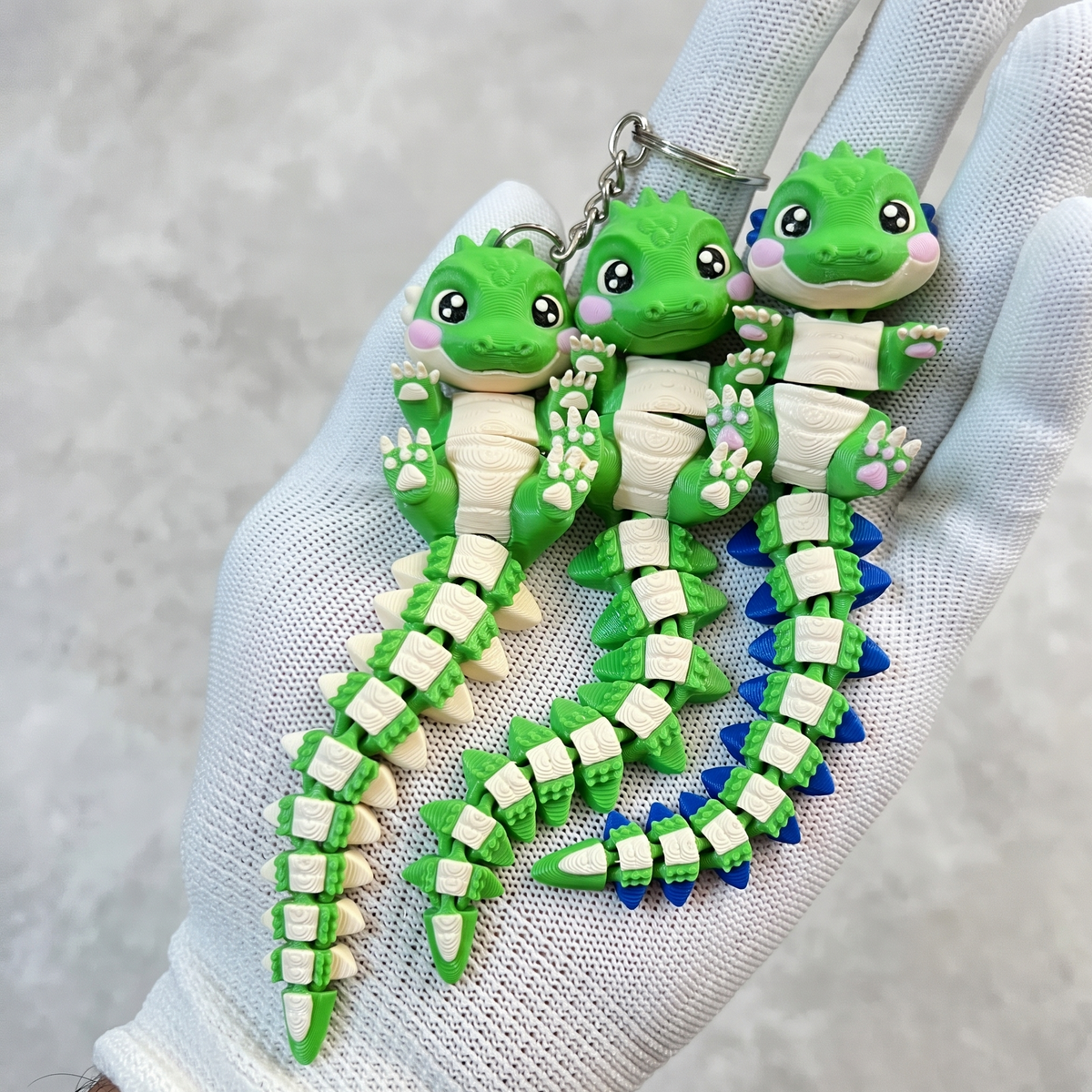 Trois porte-clés bébés crocodiles articulés kawaii aux écailles bleues, vertes et crème