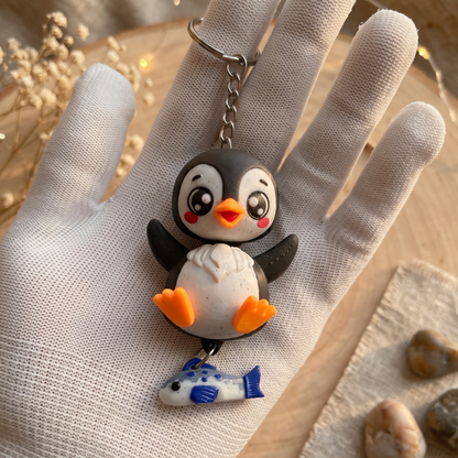 Porte-clés pingouin noir kawaii avec bec et pattes orange et poisson bleu suspendu
