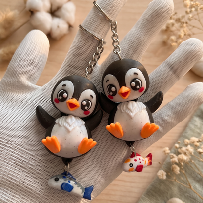 Deux porte-clés pingouins noirs kawaii avec poisson suspendu bleu ou corail