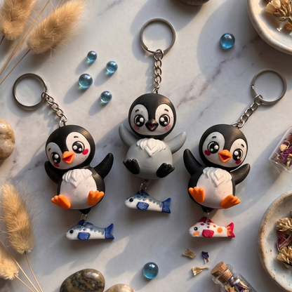 Trois porte-clés pingouins en impression 3D, modèles noir et gris avec poissons colorés