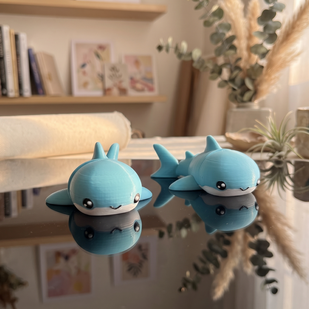Deux requins articulés kawaii bleu lagon présentés sur une surface miroir
