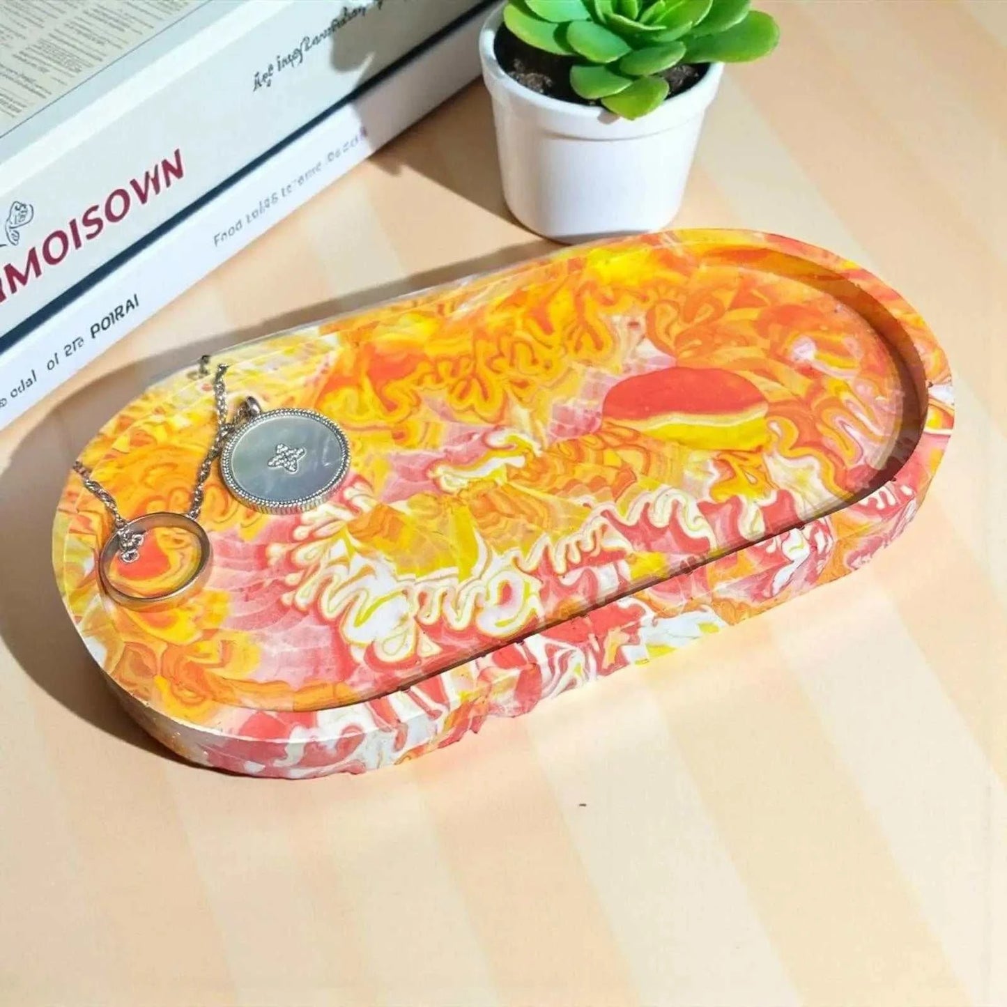 Vide-poche ovale en Jesmonite avec dégradé rouge, jaune et orangé, finition satinée et effet marbré unique.