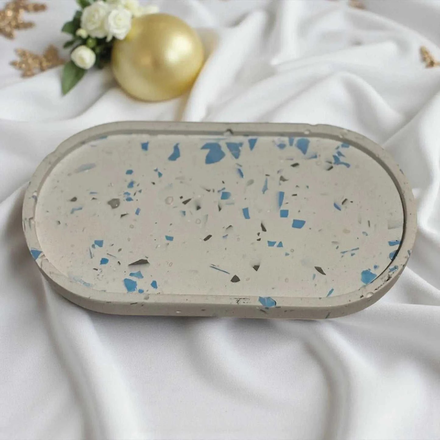 Vide-poche ovale en Jesmonite blanc terrazzo avec éclats bleus et gris, design artisanal élégant et minimaliste.