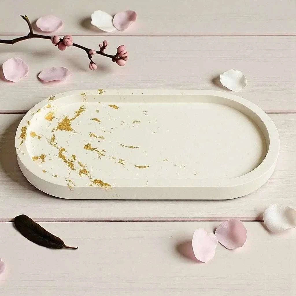 Vide-poche ovale long en Jesmonite blanche avec touches délicates de feuille d’or, finition satinée, design élégant et artisanal made in France.
