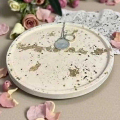 Vide-poche rond blanc en Jesmonite avec feuilles et paillettes dorées, élégant et artisanal.